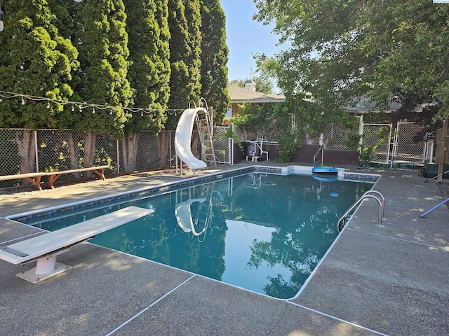 view of swimming pool with a diving board and a water slide