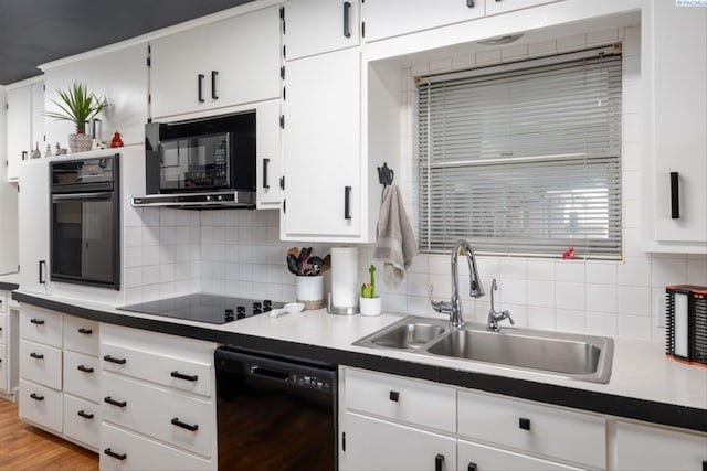 kitchen featuring sink, white cabinets, backsplash, and black appliances