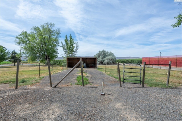 view of gate with a rural view and an outbuilding