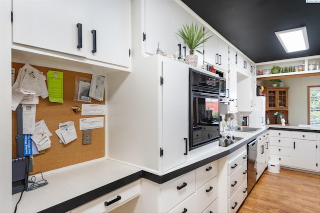 kitchen featuring white cabinetry, stainless steel dishwasher, oven, and light hardwood / wood-style flooring