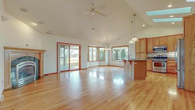 kitchen with a kitchen bar, decorative light fixtures, a center island with sink, stainless steel appliances, and light hardwood / wood-style floors