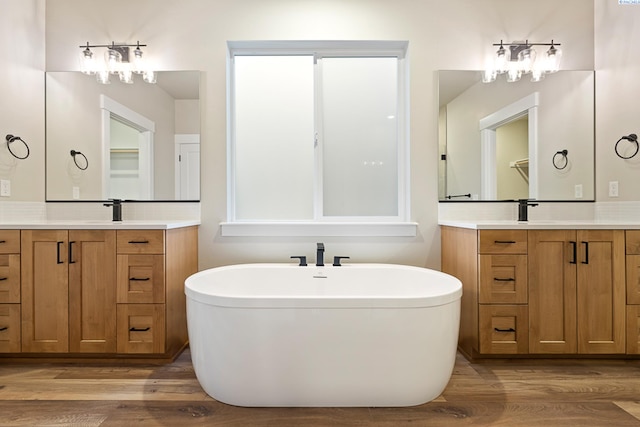 bathroom with vanity, a bath, and wood-type flooring