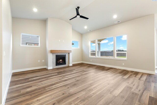 unfurnished living room featuring a tile fireplace, lofted ceiling, ceiling fan, and light hardwood / wood-style flooring