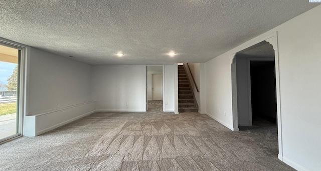 carpeted spare room with stairs, baseboards, and a textured ceiling