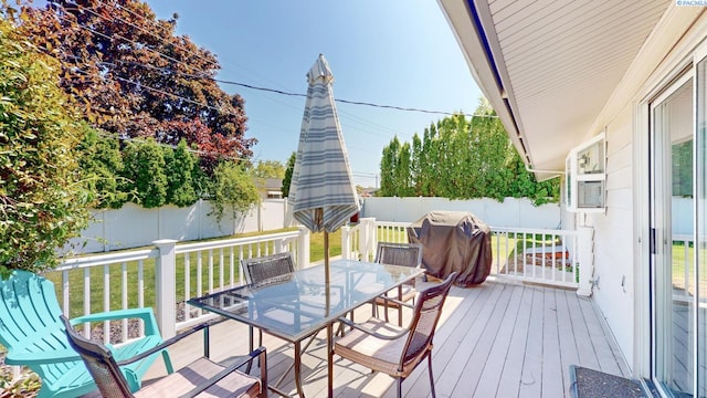 wooden terrace featuring area for grilling, outdoor dining area, and a fenced backyard