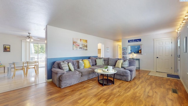 living area featuring light wood-style floors, baseboards, ceiling fan, and visible vents