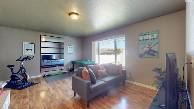 living room with baseboards, a textured ceiling, and wood finished floors
