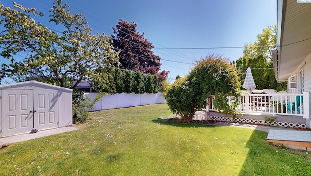 view of yard with a storage shed, fence, an outdoor structure, and a deck