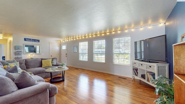 living area with visible vents, wood finished floors, and a healthy amount of sunlight
