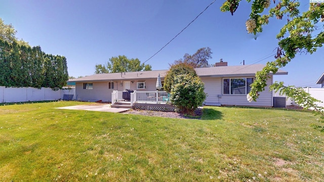 rear view of house featuring a lawn, fence, a wooden deck, and central air condition unit