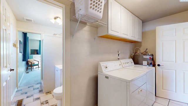 washroom with laundry area, water heater, light tile patterned floors, visible vents, and washing machine and dryer