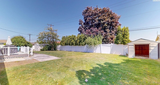 view of yard featuring a storage shed, a detached garage, a deck, a fenced backyard, and an outdoor structure