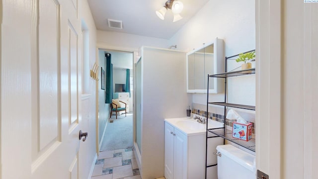 bathroom featuring visible vents, decorative backsplash, toilet, and vanity