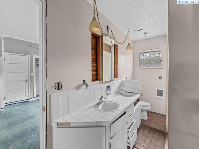 bathroom with vanity, toilet, hardwood / wood-style floors, and a textured ceiling