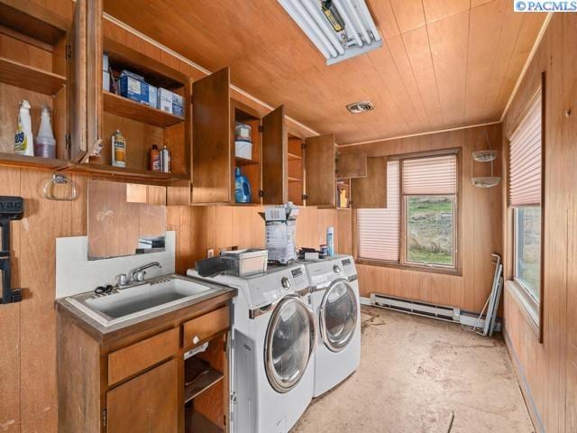 laundry area with sink, wood ceiling, a baseboard heating unit, independent washer and dryer, and wood walls