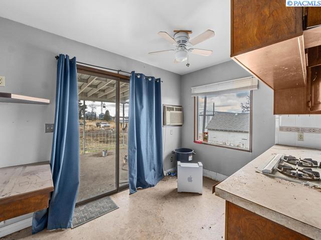 kitchen featuring decorative backsplash, a wall unit AC, stainless steel gas cooktop, and ceiling fan