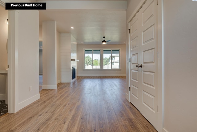 foyer entrance featuring a glass covered fireplace, baseboards, and wood finished floors