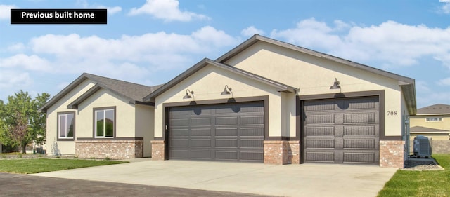 ranch-style house with brick siding, stucco siding, concrete driveway, an attached garage, and central AC