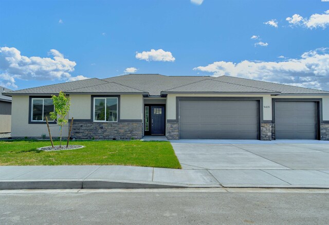 9418 Balflour Ct, Pasco, WA 99301 - prairie-style home featuring an attached garage, stucco siding, driveway, a front yard, and stone siding