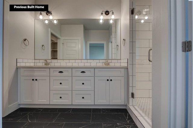 full bath with double vanity, marble finish floor, a shower stall, and a sink