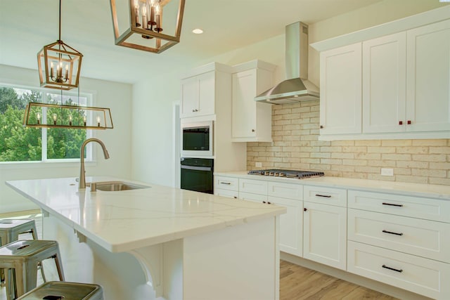 9418 Balflour Ct, Pasco, WA 99301 - kitchen featuring a sink, wall chimney exhaust hood, a chandelier, stainless steel gas stovetop, and light stone countertops