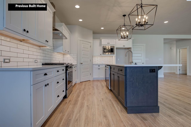 kitchen featuring white cabinets, light wood-style flooring, stainless steel appliances, and decorative backsplash