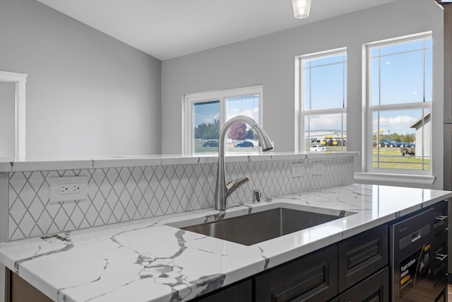 kitchen featuring tasteful backsplash, sink, and light stone counters