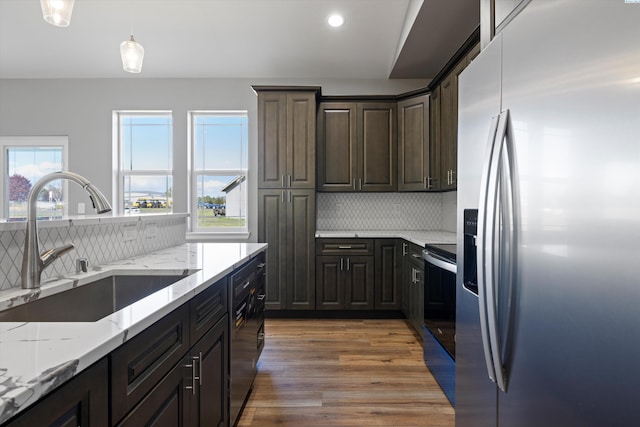 kitchen featuring sink, dark brown cabinets, stainless steel appliances, light stone countertops, and decorative light fixtures