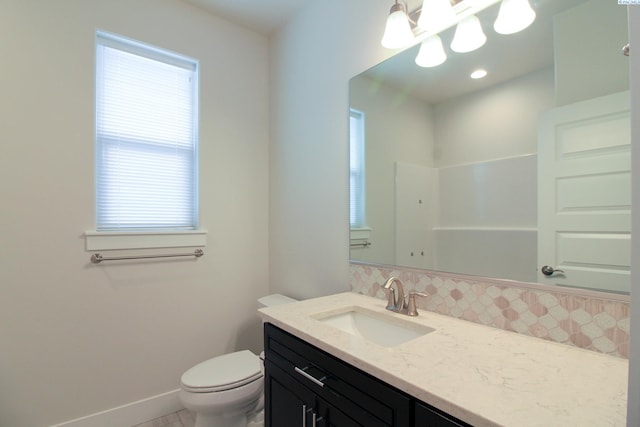 bathroom featuring healthy amount of natural light, vanity, toilet, and tasteful backsplash