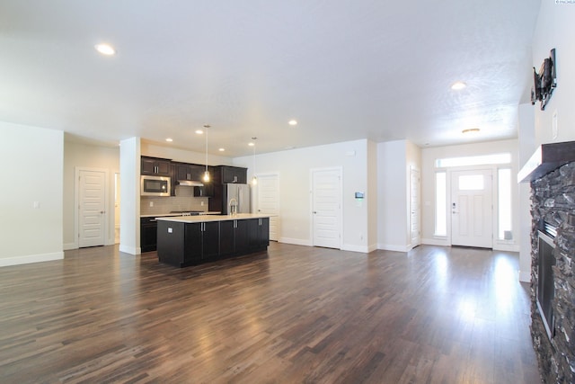 kitchen featuring appliances with stainless steel finishes, open floor plan, a kitchen island with sink, light countertops, and recessed lighting