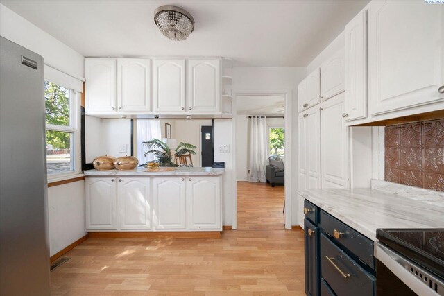 3011 W Hood Ave, Kennewick, WA 99336 - kitchen featuring white cabinets, light wood-style flooring, light countertops, baseboards, and freestanding refrigerator