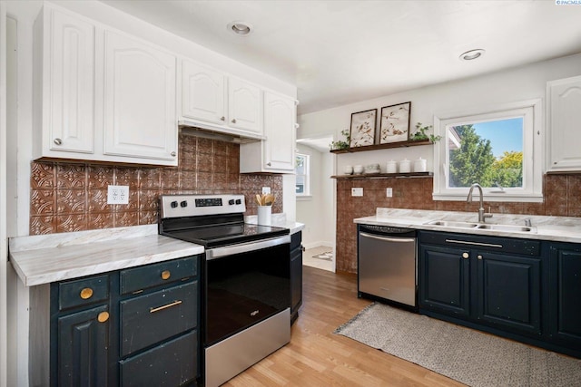 3011 W Hood Ave, Kennewick, WA 99336 - kitchen with appliances with stainless steel finishes, a sink, white cabinets, decorative backsplash, and light wood-type flooring