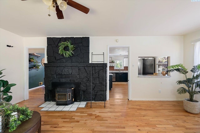 3011 W Hood Ave, Kennewick, WA 99336 - living area with light wood finished floors, a wood stove, a ceiling fan, and baseboards