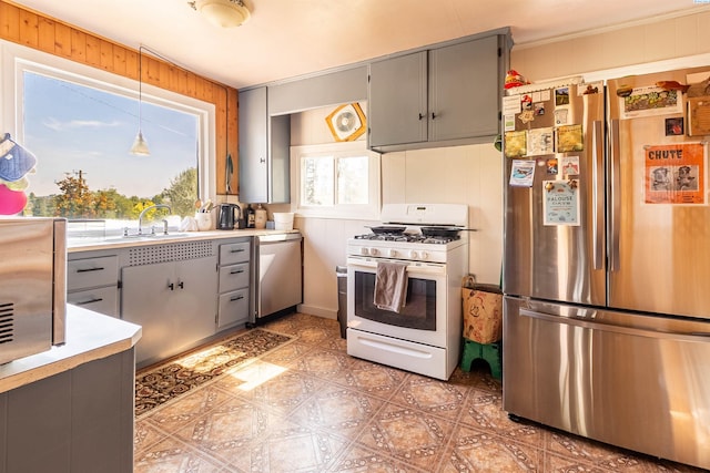 kitchen with hanging light fixtures, gray cabinets, stainless steel appliances, and sink