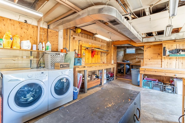 basement with wooden walls, washer and clothes dryer, and a workshop area