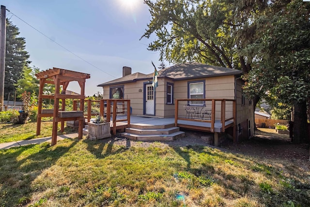 back of property featuring a pergola, a deck, and a lawn