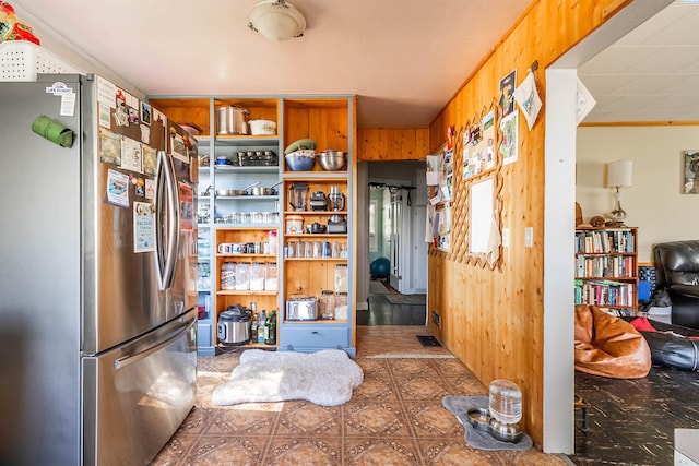 kitchen featuring stainless steel refrigerator and wood walls