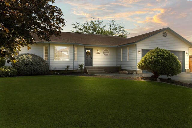 ranch-style home featuring a garage and a lawn