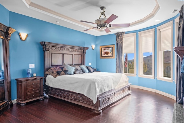 bedroom with a raised ceiling, dark wood-type flooring, and ceiling fan