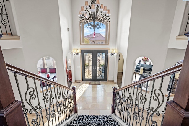 entrance foyer featuring a high ceiling, a wealth of natural light, a notable chandelier, and french doors