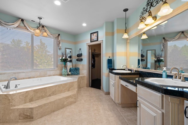 bathroom with tile patterned flooring, vanity, and a relaxing tiled tub