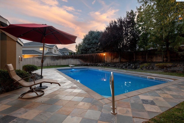 pool at dusk with a diving board and a patio