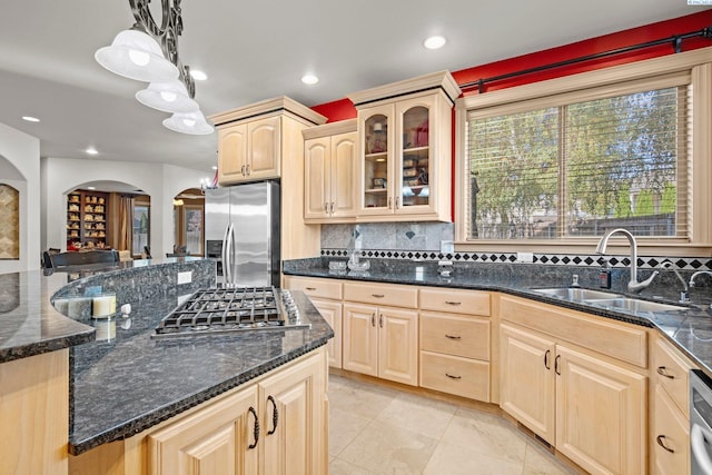 kitchen with appliances with stainless steel finishes, pendant lighting, sink, dark stone countertops, and light brown cabinets