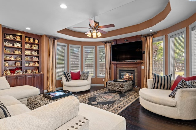 living room featuring ceiling fan, wood-type flooring, and a tray ceiling