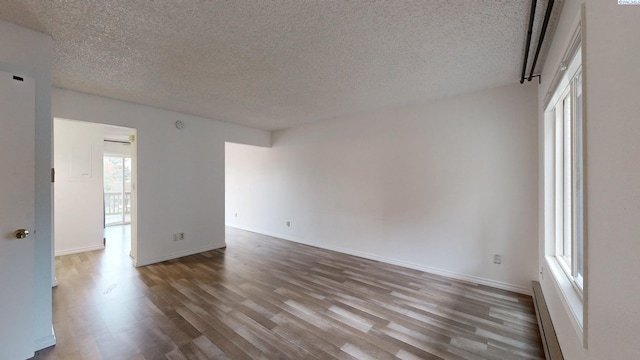 unfurnished room featuring a baseboard radiator, wood-type flooring, and a textured ceiling