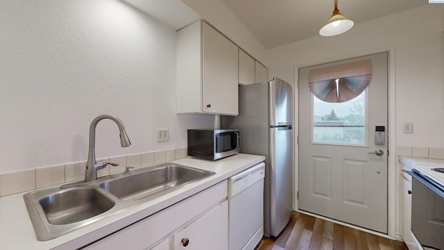 kitchen with sink, white cabinetry, hanging light fixtures, appliances with stainless steel finishes, and light hardwood / wood-style floors