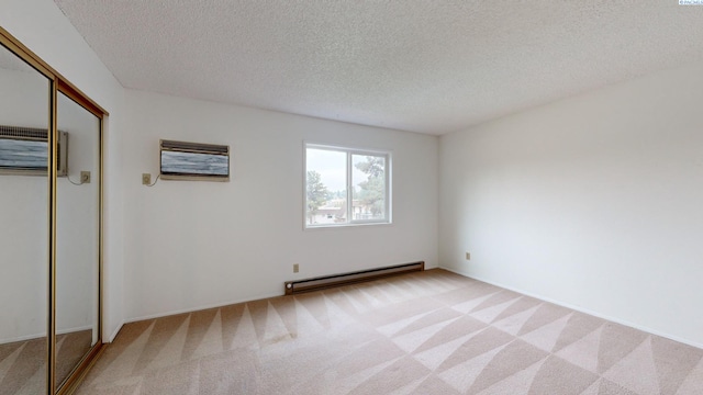 carpeted spare room with a baseboard heating unit, a wall mounted AC, and a textured ceiling