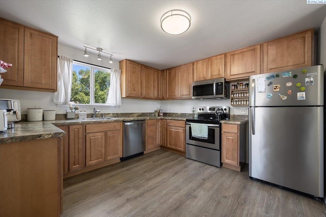 2132 Cascade Ave, Richland, WA 99354 - kitchen featuring stainless steel appliances, light wood finished floors, dark countertops, and brown cabinetry