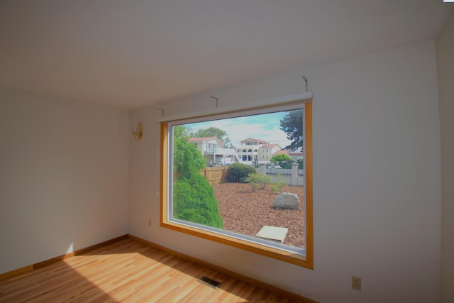 spare room featuring baseboards, visible vents, and wood finished floors