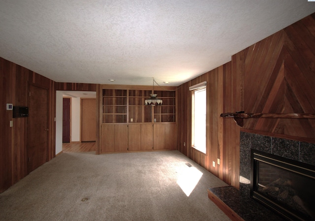 unfurnished living room featuring wooden walls, a textured ceiling, and a fireplace